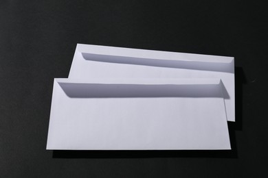 Paper envelopes on black background, above view. Mockup for design