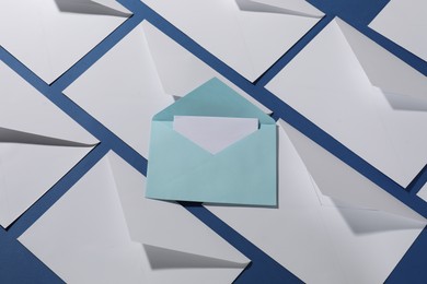 Photo of Paper envelopes with letter on blue background, flat lay. Mockup for design