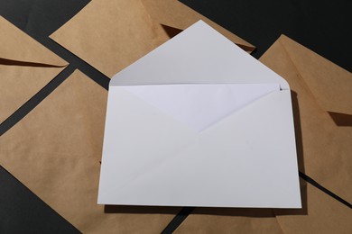 Photo of Paper envelopes with letter on black background, above view. Mockup for design