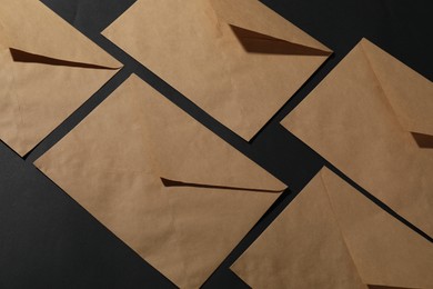 Photo of Kraft paper envelopes on black background, above view. Mockup for design