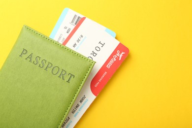 Photo of Passport with tickets on yellow background, top view. Space for text