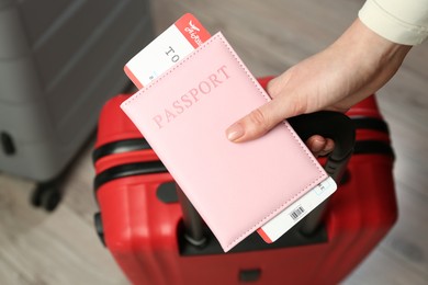 Photo of Woman with passport, ticket and suitcases indoors, closeup