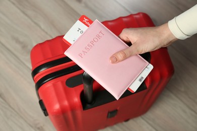 Photo of Woman with passport, ticket and suitcase indoors, closeup