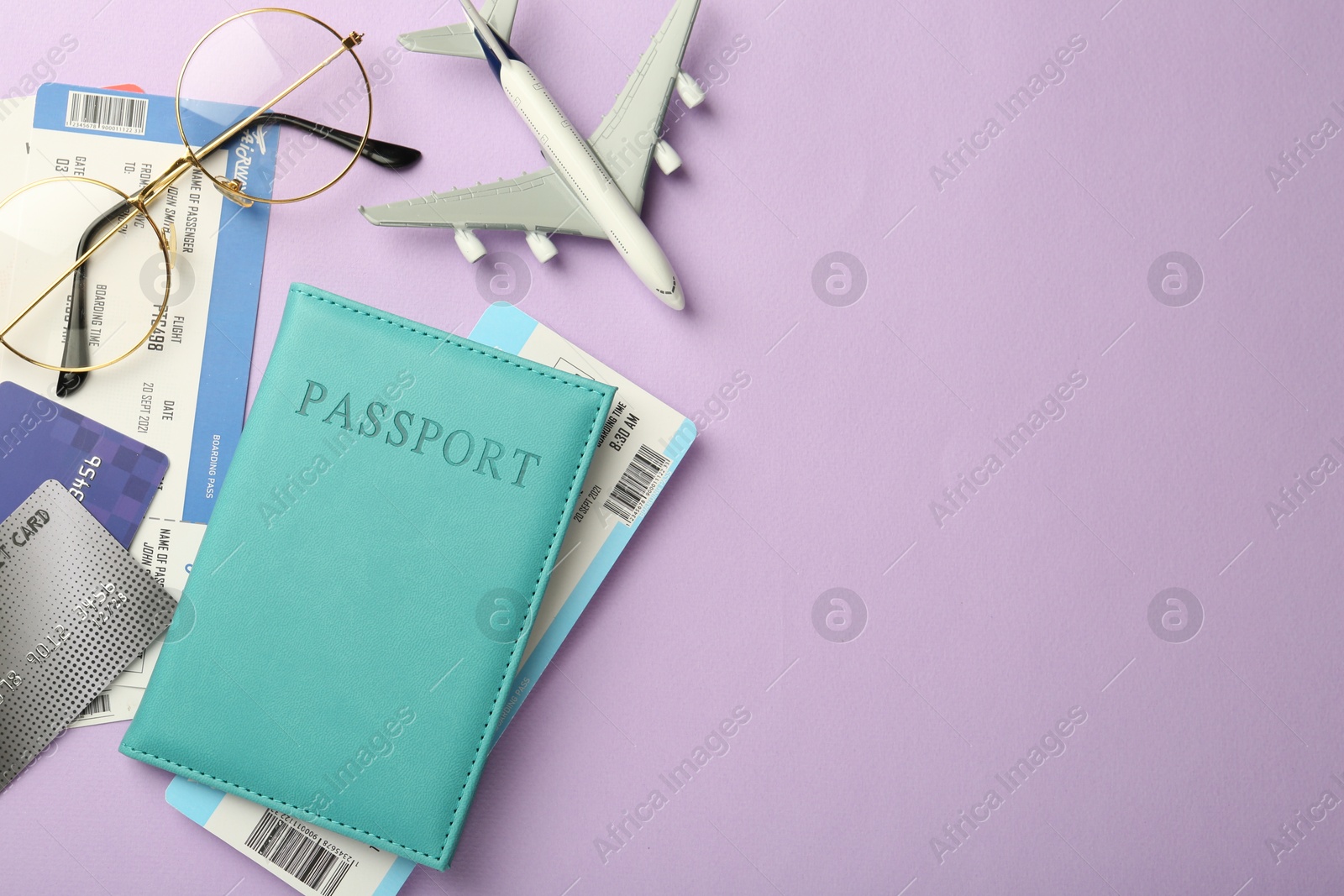 Photo of Passport with tickets, credit cards, glasses and airplane model on lilac background, flat lay. Space for text