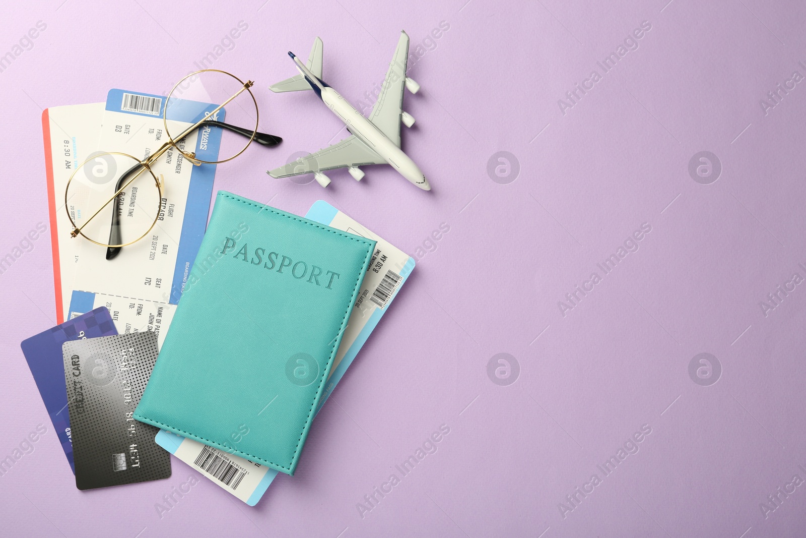 Photo of Passport with tickets, credit cards, glasses and airplane model on lilac background, flat lay. Space for text