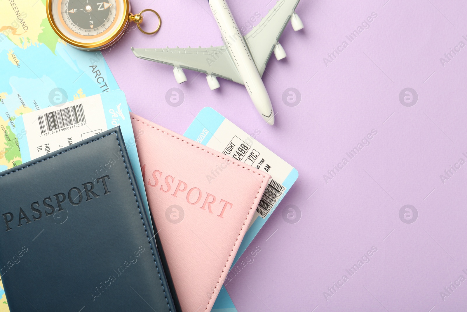 Photo of Passports with tickets, compass, map and airplane model on lilac background, flat lay. Space for text