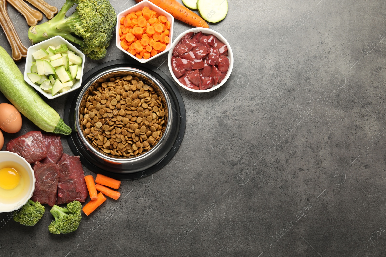 Photo of Dry pet food and natural products on grey table, top view. Space for text