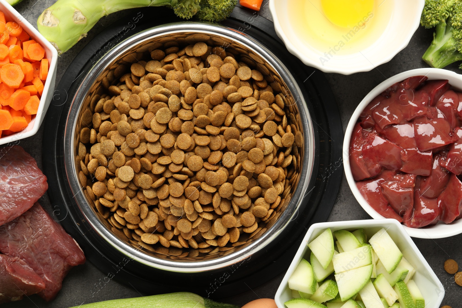 Photo of Dry pet food and natural products on grey table, top view