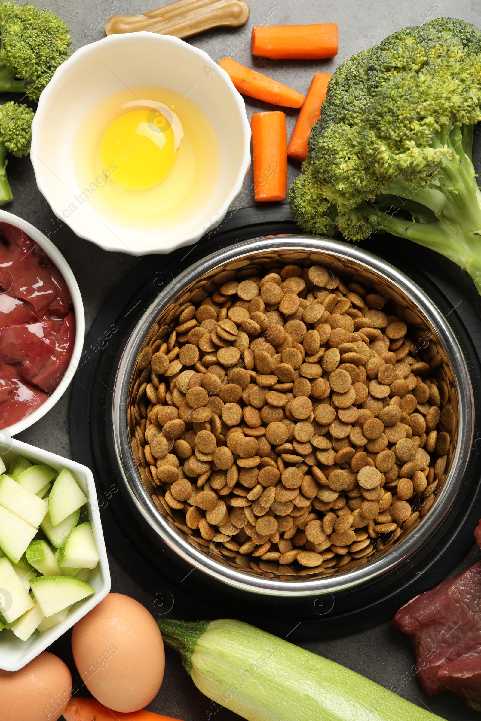 Photo of Dry pet food and natural products on grey table, top view