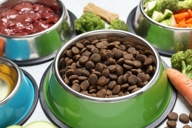 Photo of Dry pet food and natural products on light table, closeup