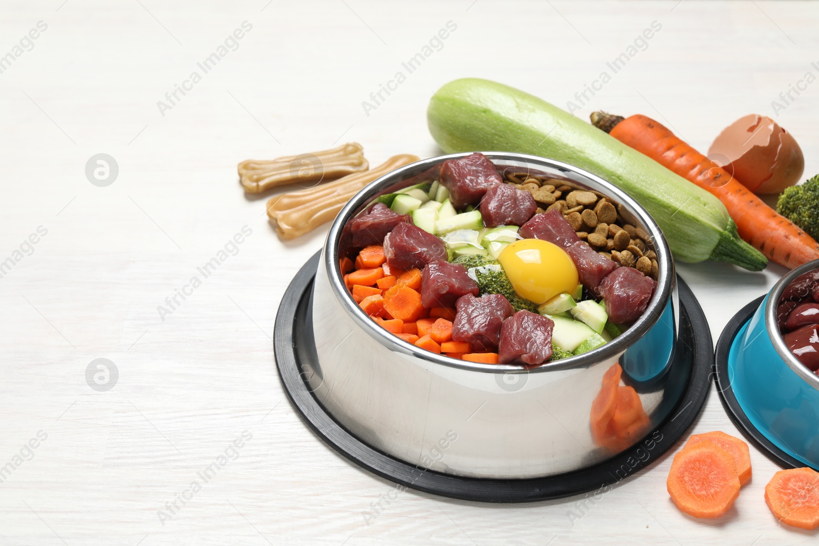 Photo of Dry pet food and natural products on white wooden table, closeup. Space for text