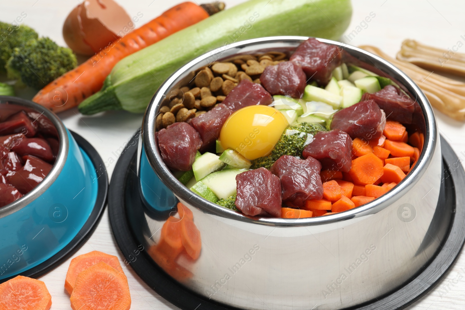 Photo of Dry pet food and natural products on white wooden table, closeup