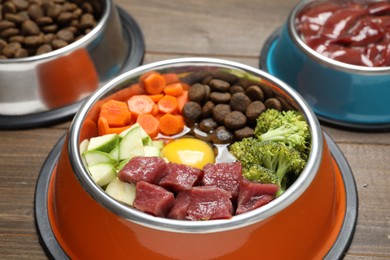 Photo of Dry pet food and natural products on wooden table, closeup