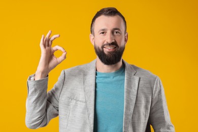 Photo of Man showing okay gesture on orange background