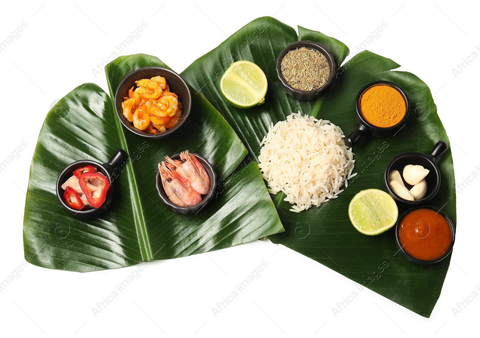 Photo of Cut banana leaves with different food, spices and sauce isolated on white, top view. Healthy eco serving