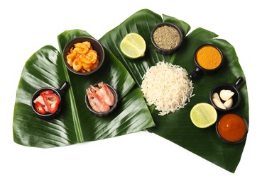 Photo of Cut banana leaves with different food, spices and sauce isolated on white, top view. Healthy eco serving