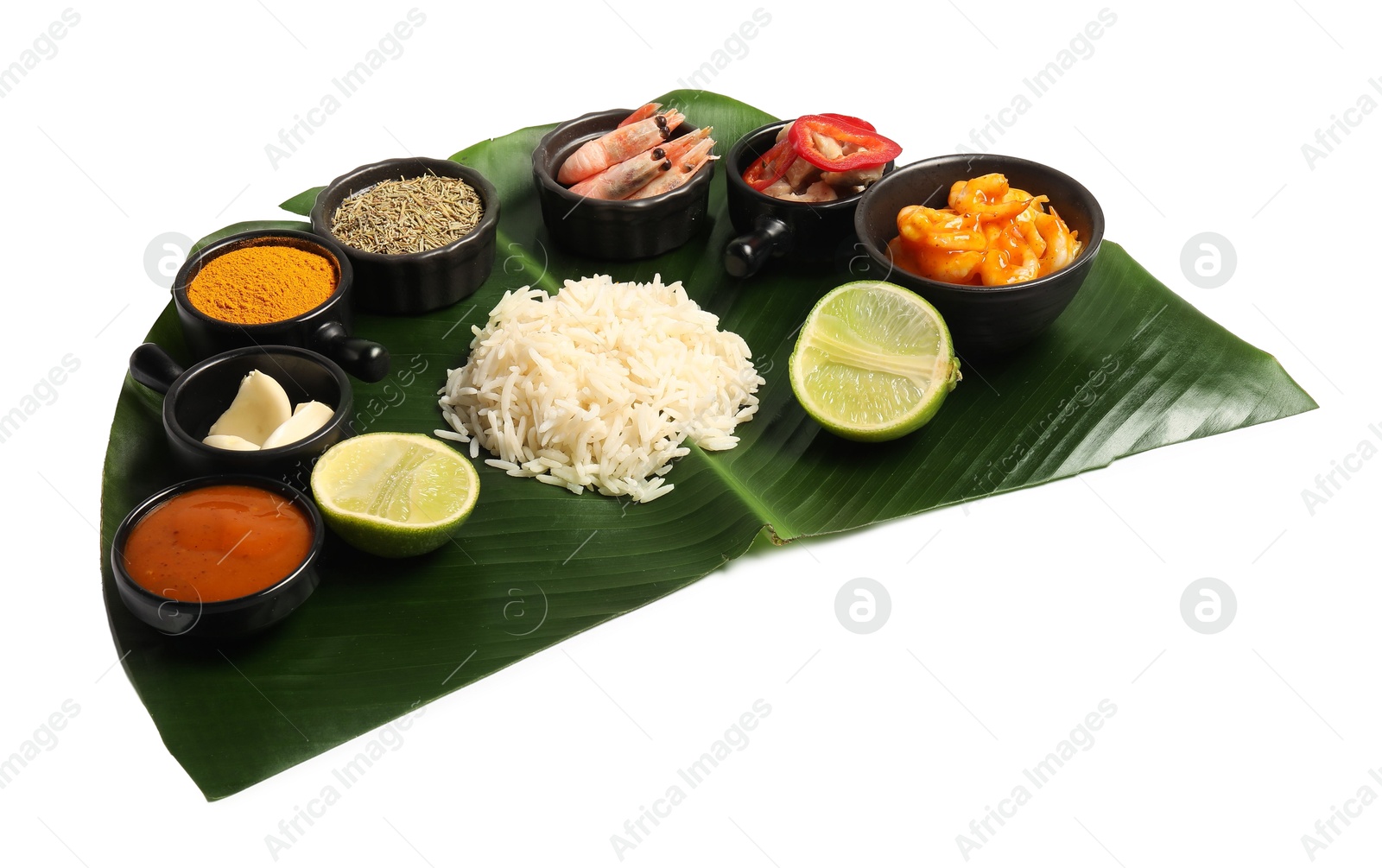 Photo of Cut banana leaf with different food, spices and sauce isolated on white. Healthy eco serving