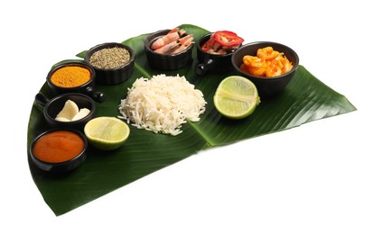 Photo of Cut banana leaf with different food, spices and sauce isolated on white. Healthy eco serving