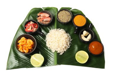 Photo of Cut banana leaf with different food, spices and sauce isolated on white, top view. Healthy eco serving