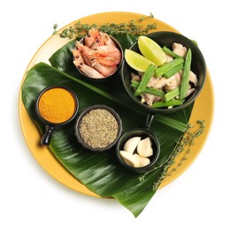 Photo of Cut banana leaf with different food and spices isolated on white, top view. Healthy eco serving