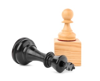 Photo of Pawn on wooden block near fallen king chess against white background. Competition concept