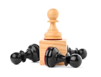 Photo of White pawn on wooden block among fallen black ones against white background. Competition concept