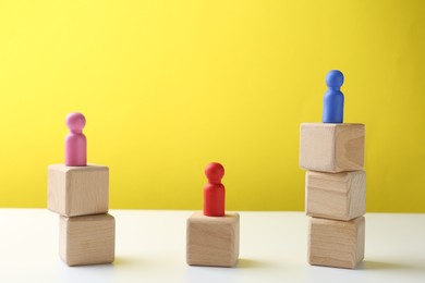 Photo of Competition concept. Human figures on wooden cubes against color background, space for text