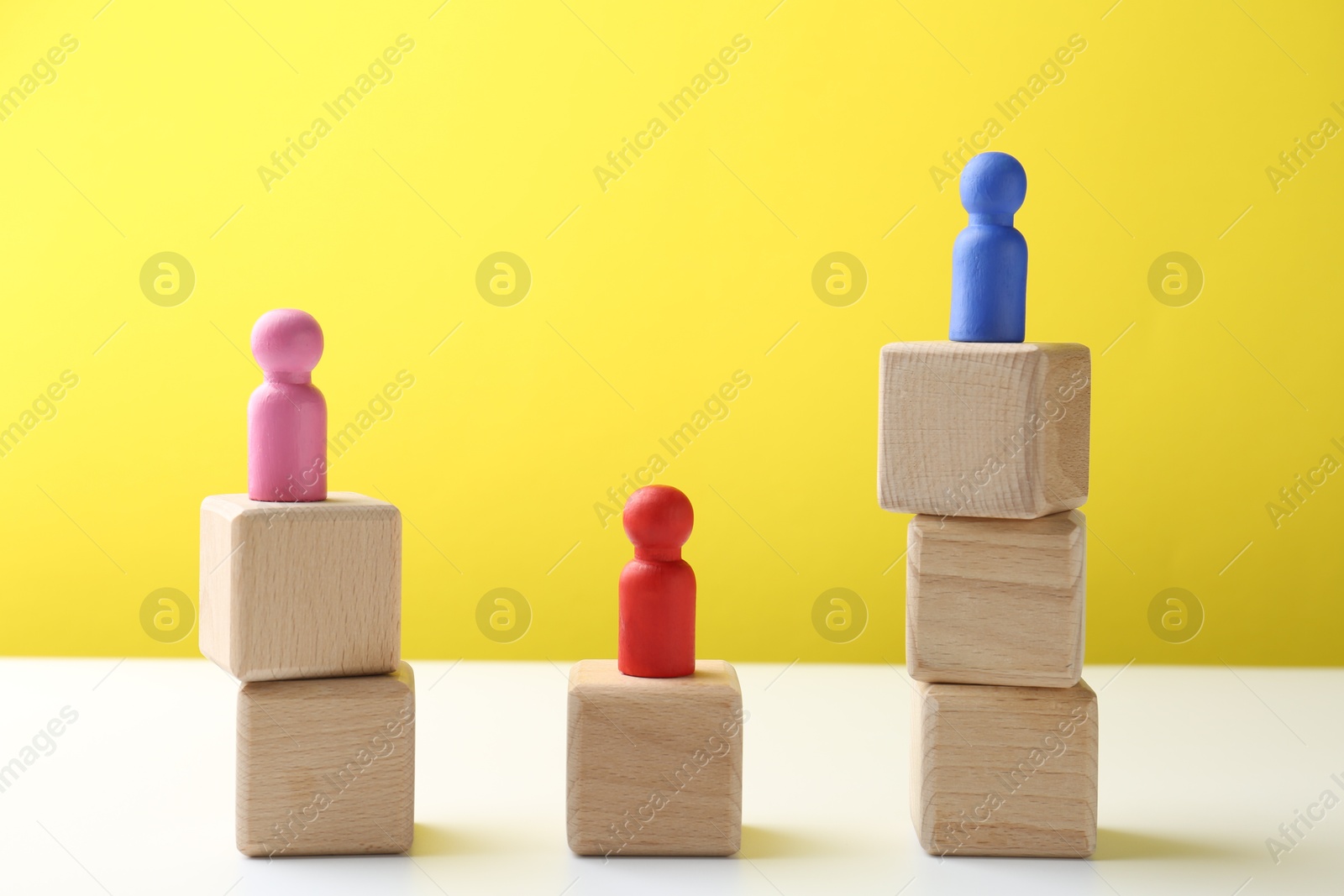 Photo of Competition concept. Human figures on wooden cubes against color background