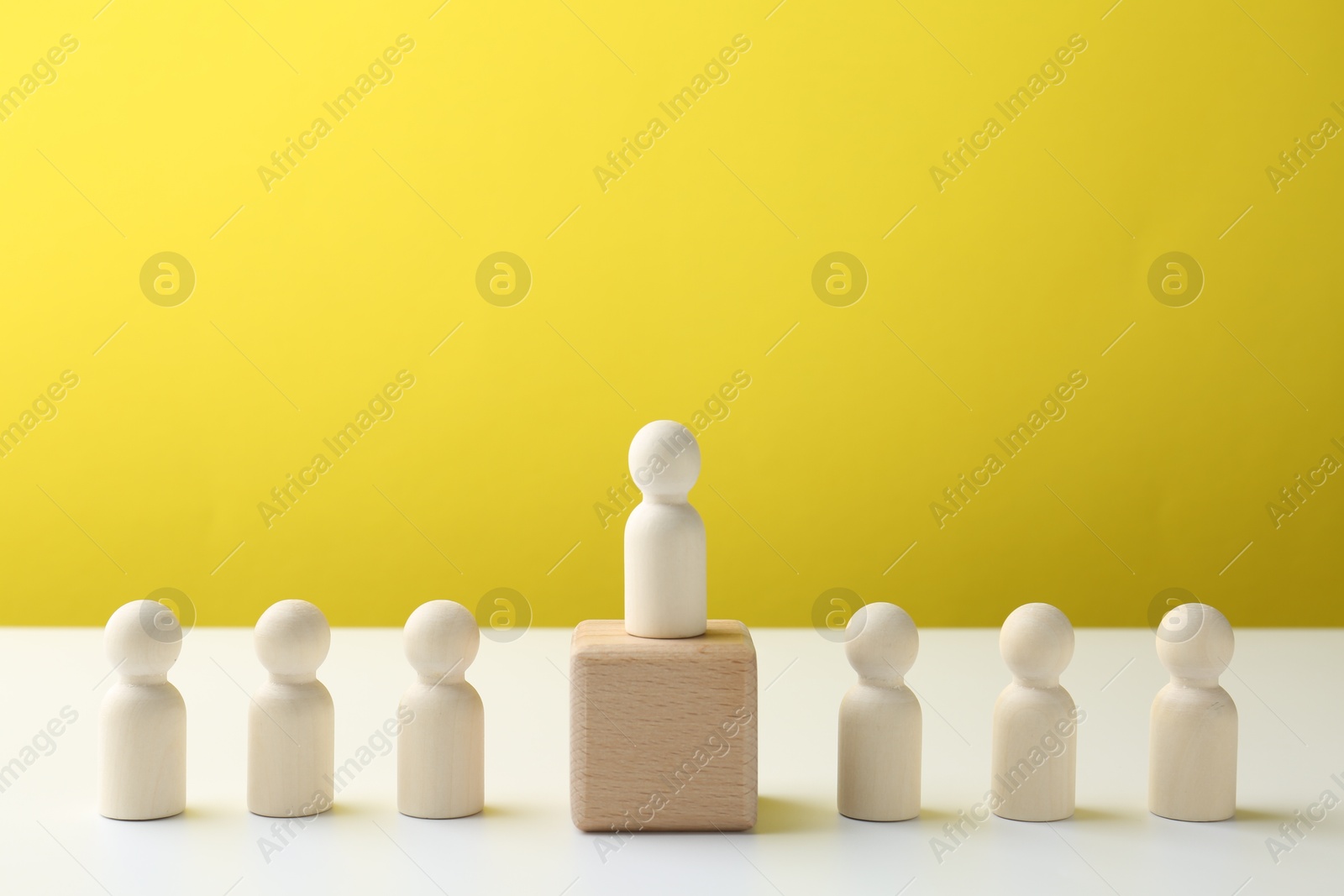 Photo of Competition concept. Human figure on wooden cube and other ones behind against color background, space for text