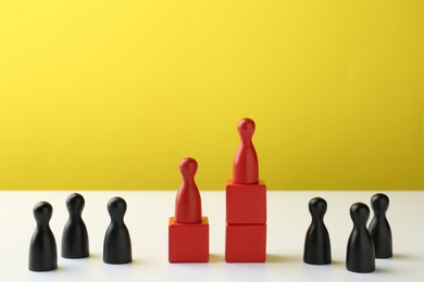 Photo of Competition concept. Human figures on wooden cubes and other ones behind against color background, space for text