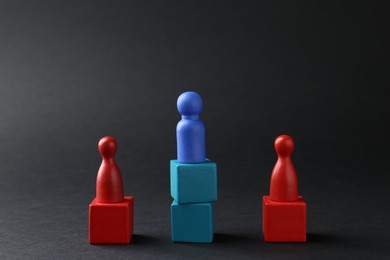 Photo of Competition concept. Human figures on wooden cubes against black background