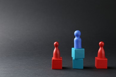 Photo of Competition concept. Human figures on wooden cubes against black background, space for text