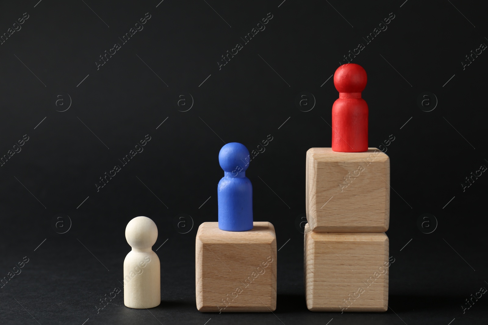 Photo of Competition concept. Human figures on wooden cubes against black background