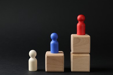 Photo of Competition concept. Human figures on wooden cubes against black background