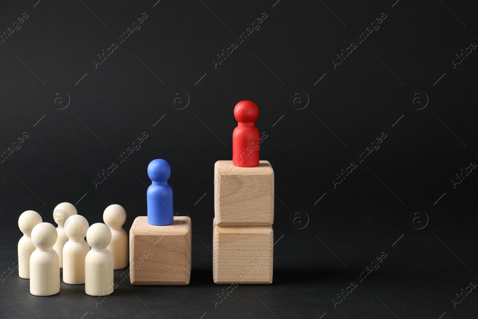 Photo of Competition concept. Human figures on wooden cubes and other ones behind against black background, space for text