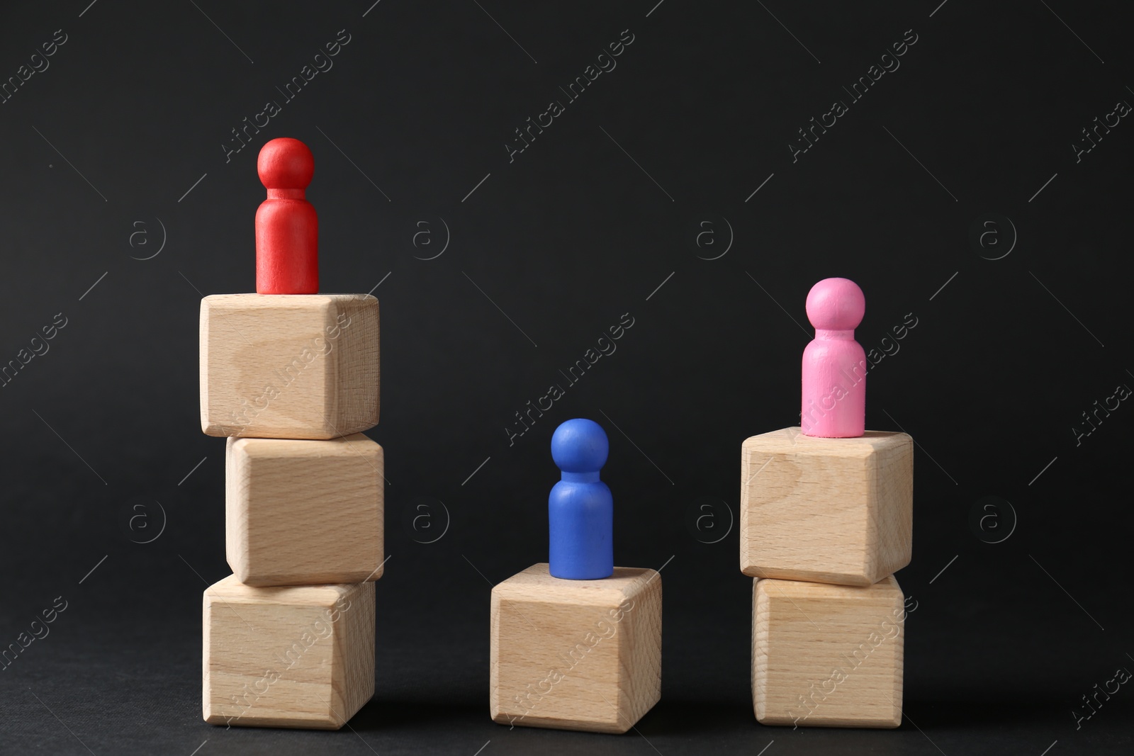 Photo of Competition concept. Human figures on wooden cubes against black background