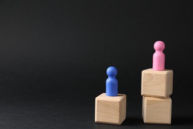 Photo of Competition concept. Human figures on wooden cubes against black background, space for text