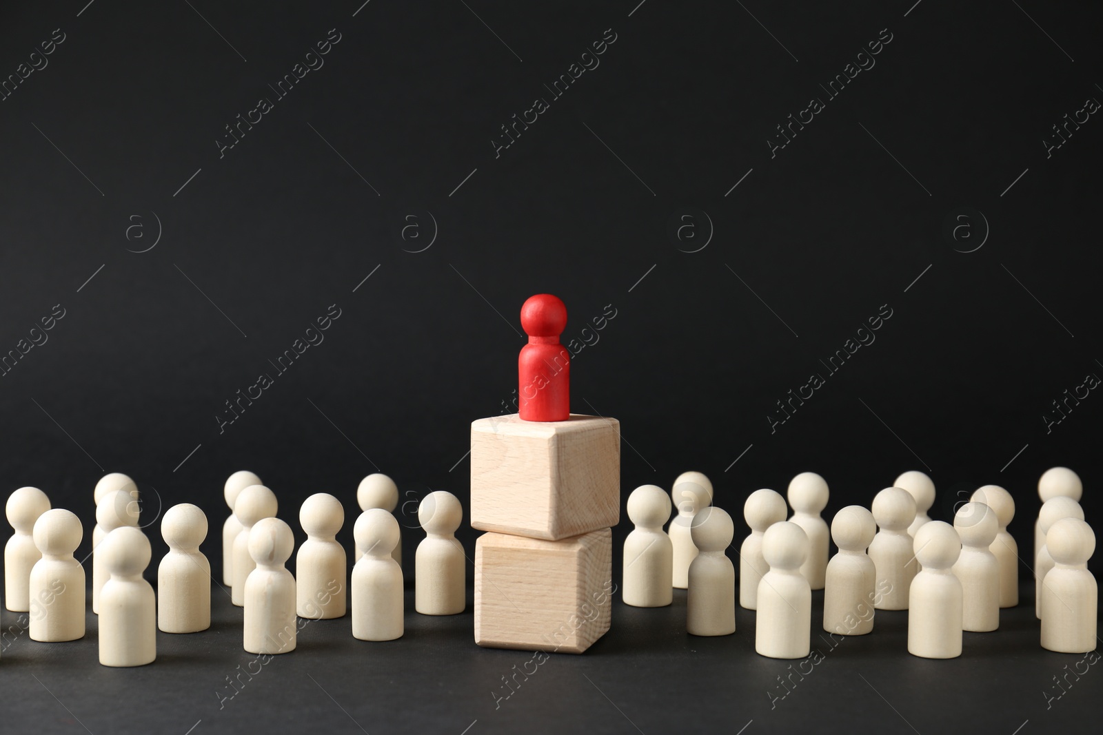 Photo of Competition concept. Human figure on wooden cubes and other ones behind against black background