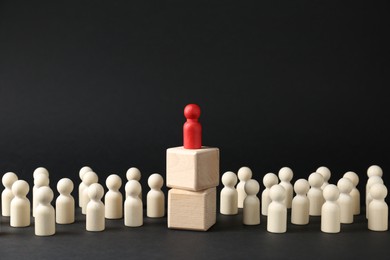 Photo of Competition concept. Human figure on wooden cubes and other ones behind against black background