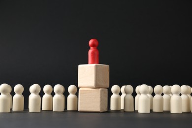 Photo of Competition concept. Human figure on wooden cubes and other ones behind against black background