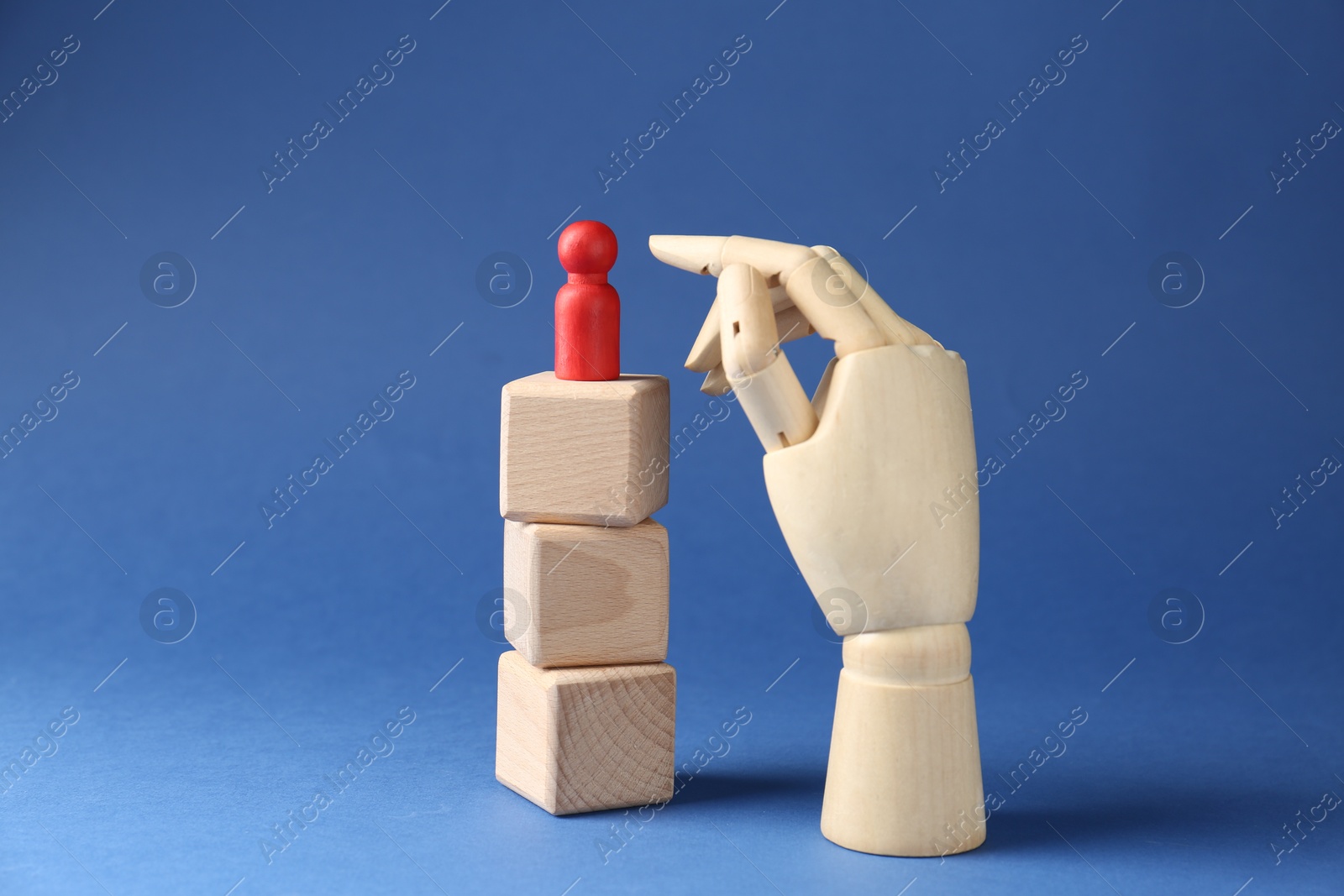 Photo of Competition concept. Human figure on wooden cubes and hand model against blue background