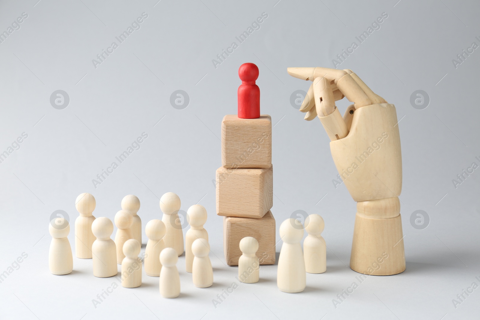 Photo of Competition concept. Human figure on wooden cubes, other ones behind and hand model against light background