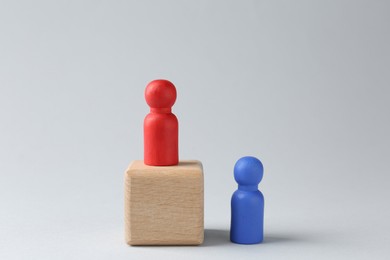 Photo of Competition concept. Human figure on wooden cube and other one behind against light background