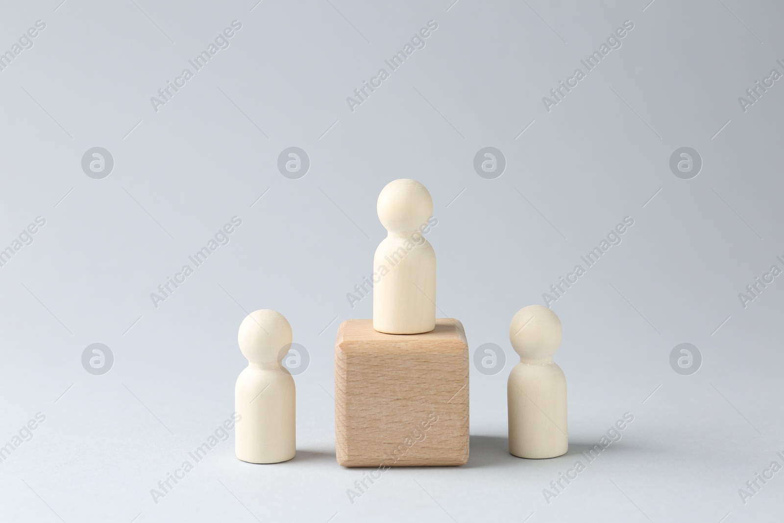 Photo of Competition concept. Human figure on wooden cube and other ones behind against light background