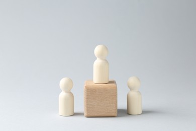 Photo of Competition concept. Human figure on wooden cube and other ones behind against light background