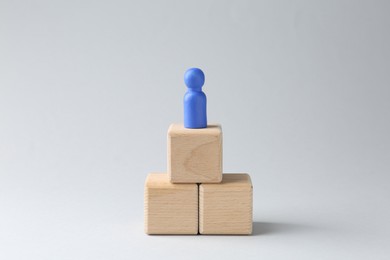 Photo of Competition concept. Human figure on wooden cubes against light background