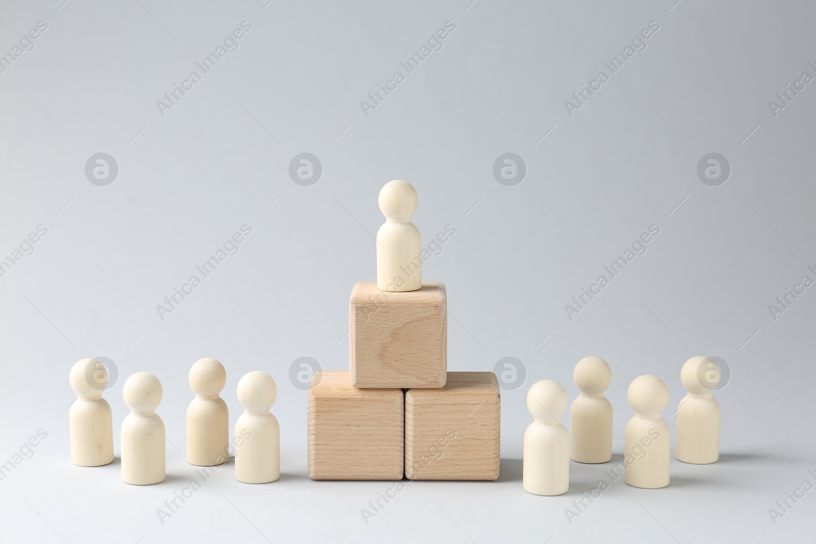 Photo of Competition concept. Human figure on wooden cubes and other ones behind against light background