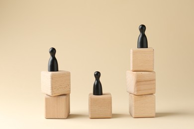 Competition concept. Human figures on wooden cubes against beige background