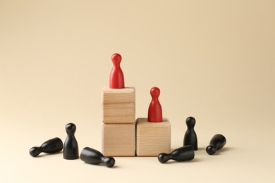 Competition concept. Human figures on wooden cubes and other ones behind against beige background