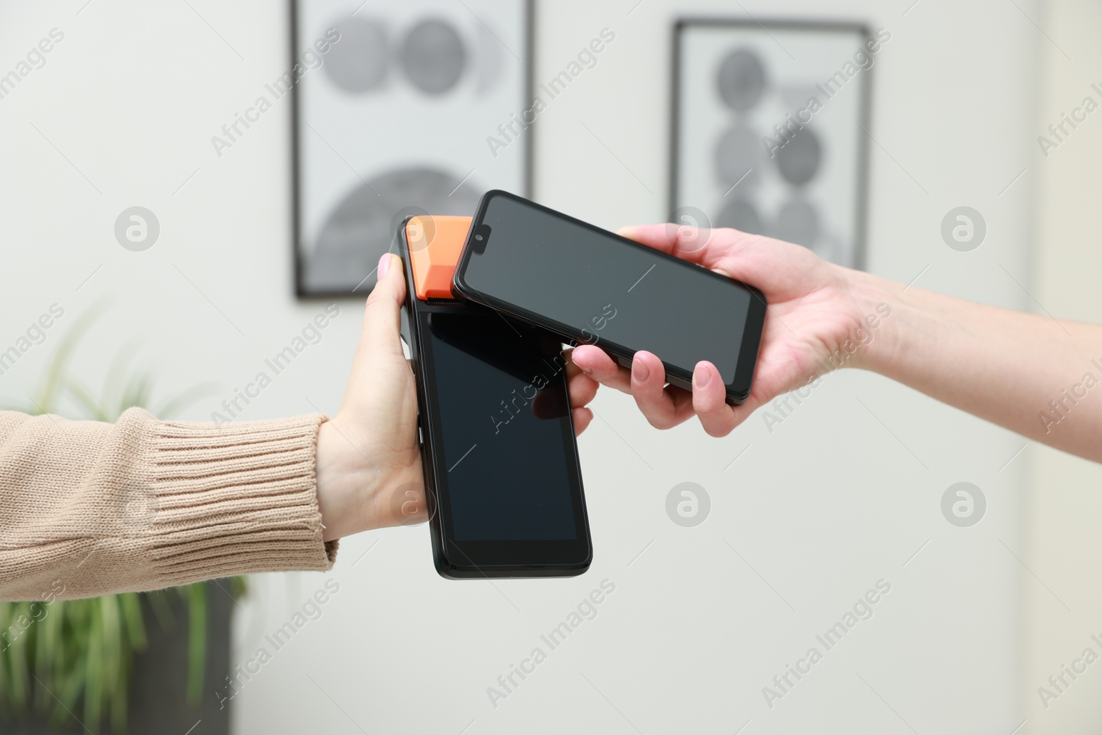 Photo of Woman paying for service with smartphone via terminal indoors, closeup